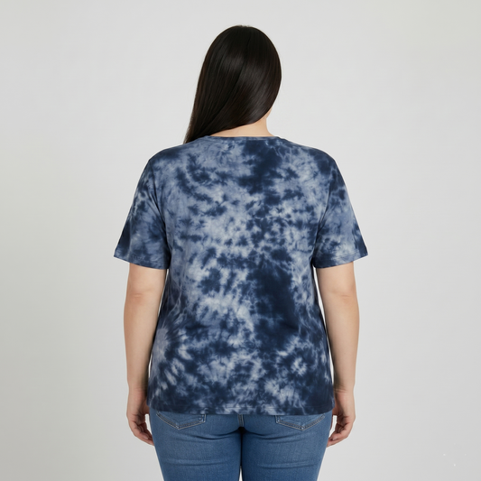 Person wearing a blue tie-dye t-shirt and jeans on a plain background