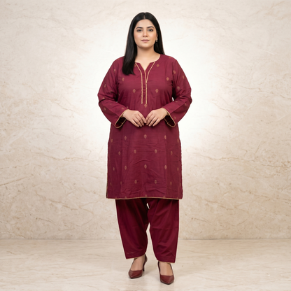 Woman wearing a maroon traditional outfit with gold details against a beige background