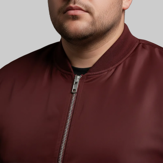 Maroon plus size bomber jacket with front zip closure and ribbed cuffs on a plain background.