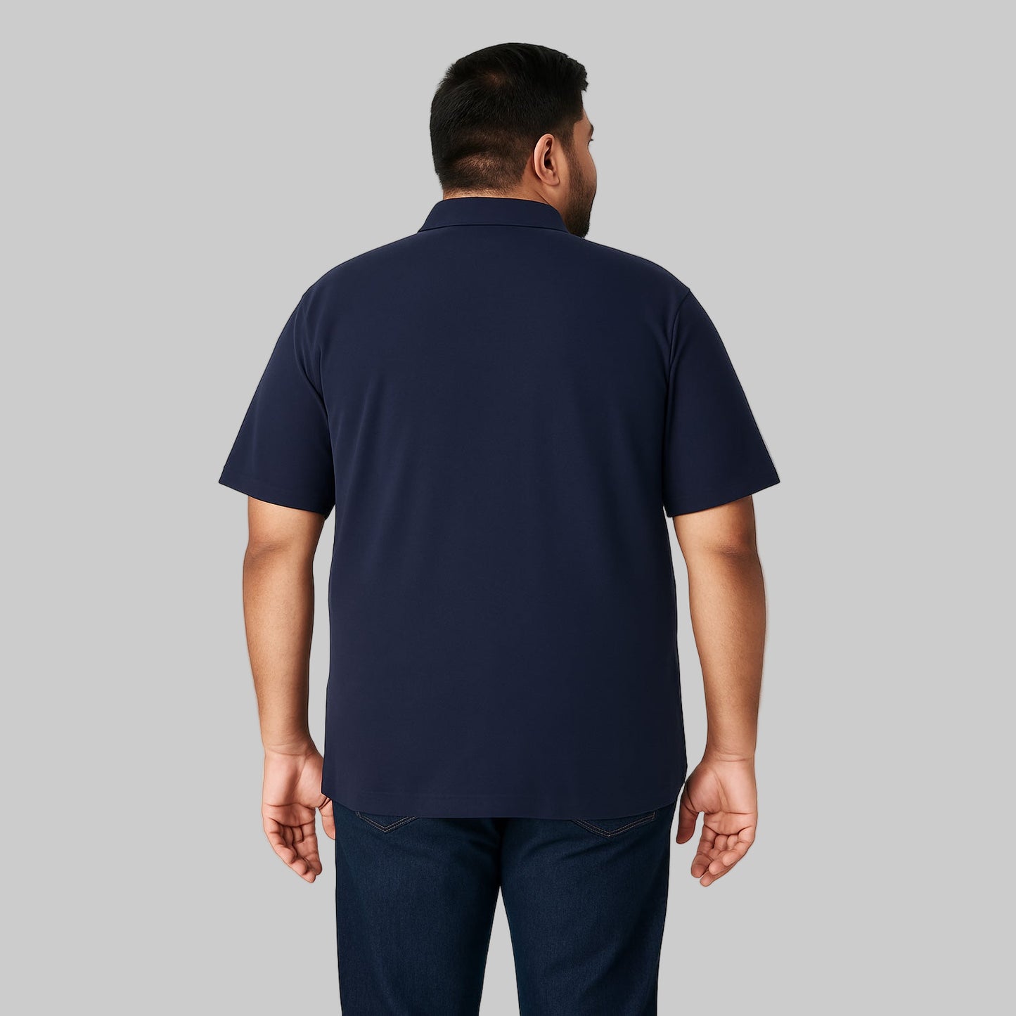 Plus-size Pakistani male model wearing navy blue piqué polo shirt with dark jeans on a light-gray background, front and back views, relaxed fit.