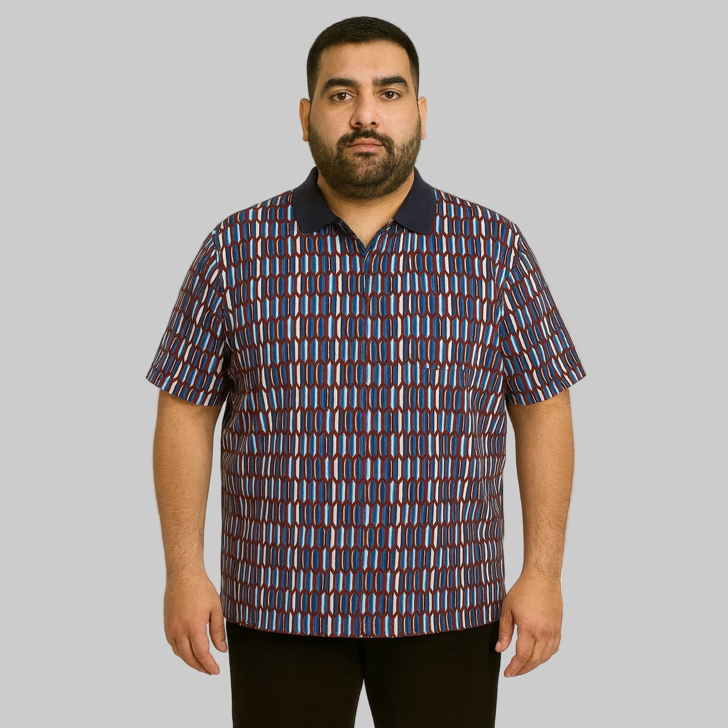 Plus-size Pakistani male model wearing navy geo colorblock quarter-zip polo shirt with ribbed collar on a clean studio background.