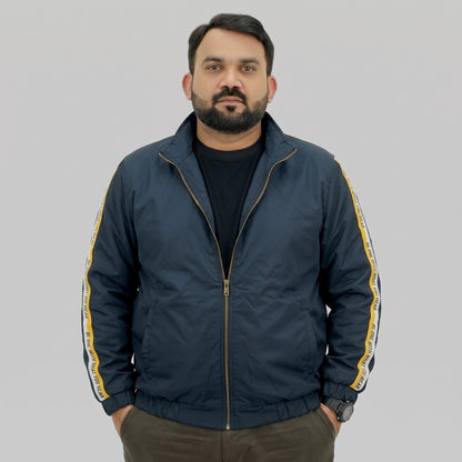 Navy blue polyester jacket with yellow and white side stripes printed with “BE ONE WITH WHAT YOU WEAR” text.