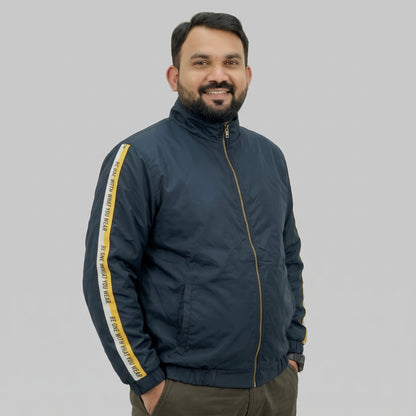  Navy blue polyester jacket with yellow and white side stripes printed with “BE ONE WITH WHAT YOU WEAR” text.