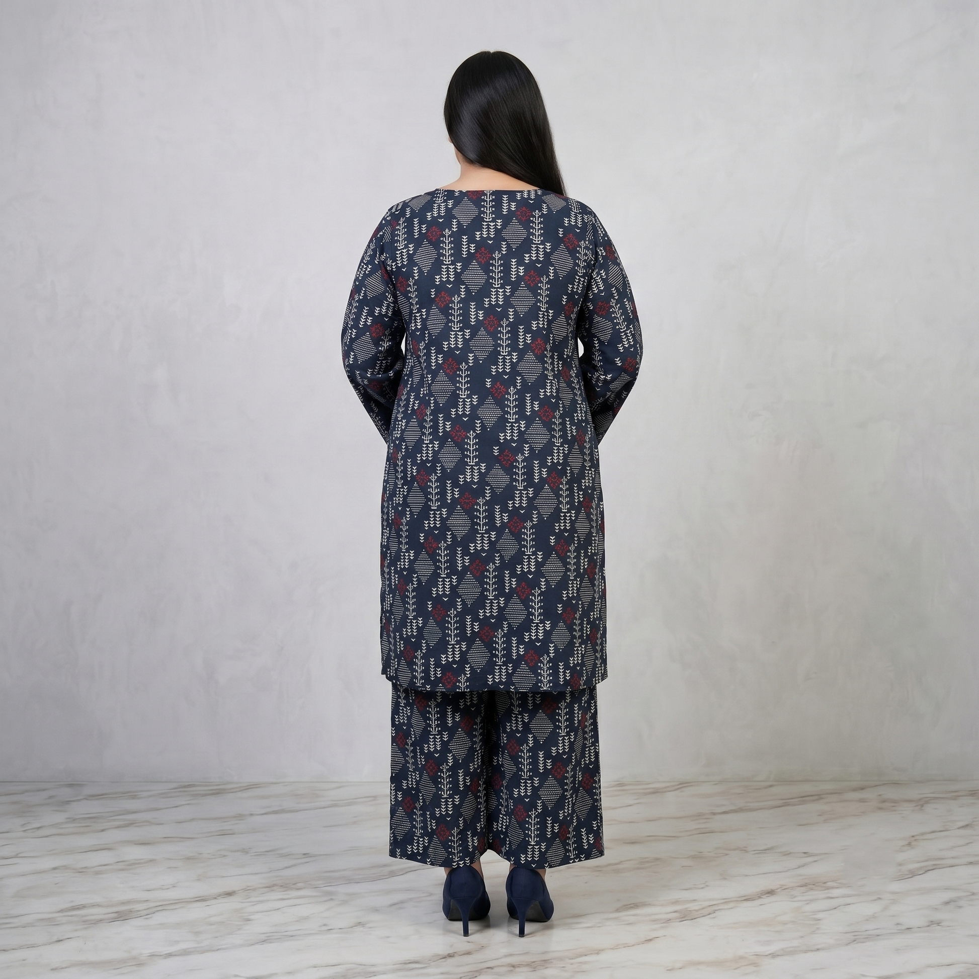 Woman wearing a patterned outfit standing against a plain background