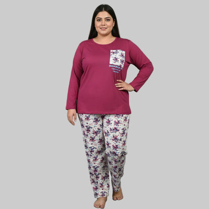 Plus-size woman wearing a plum cotton pajama set with floral white trousers and a printed pocket top on a gray studio background.