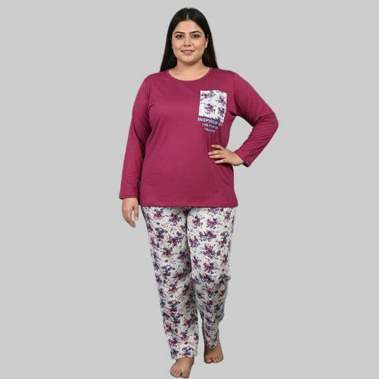 Plus-size woman wearing a plum cotton pajama set with floral white trousers and a printed pocket top on a gray studio background.