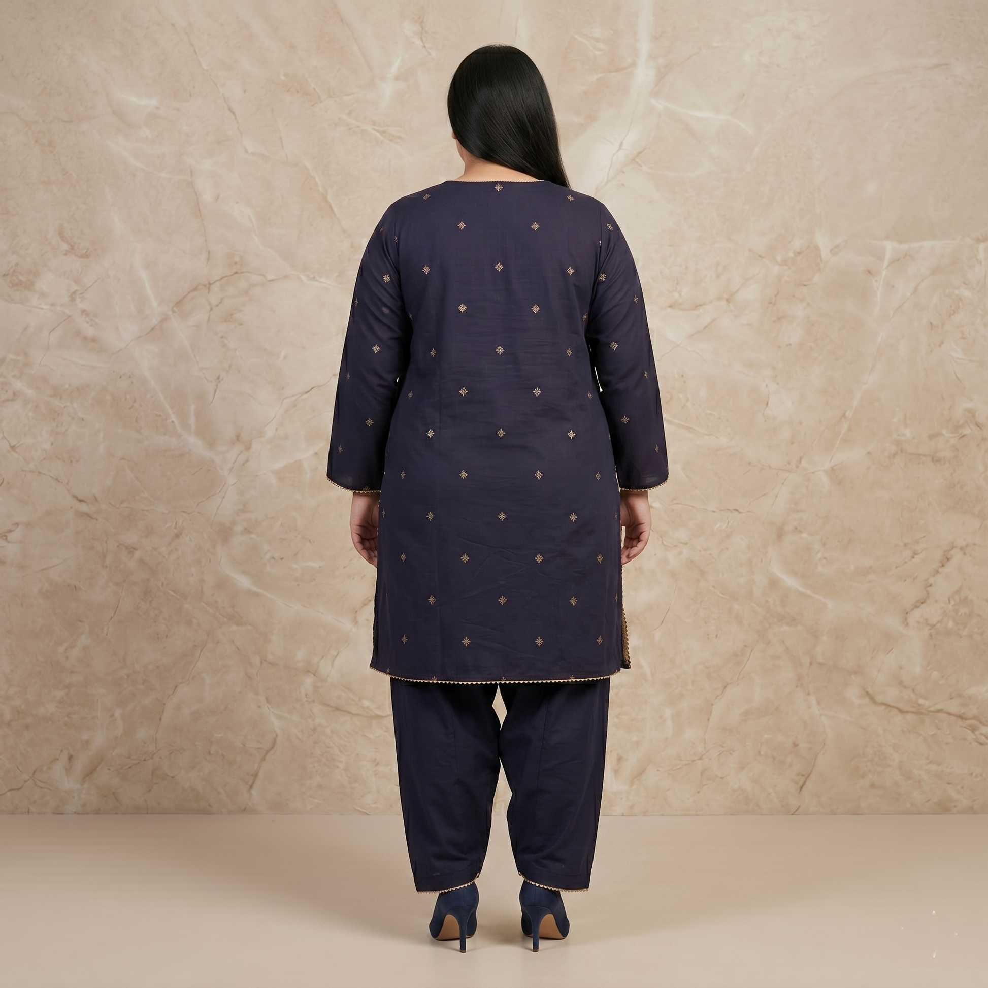 Woman wearing a navy blue traditional outfit with gold patterns against a beige background