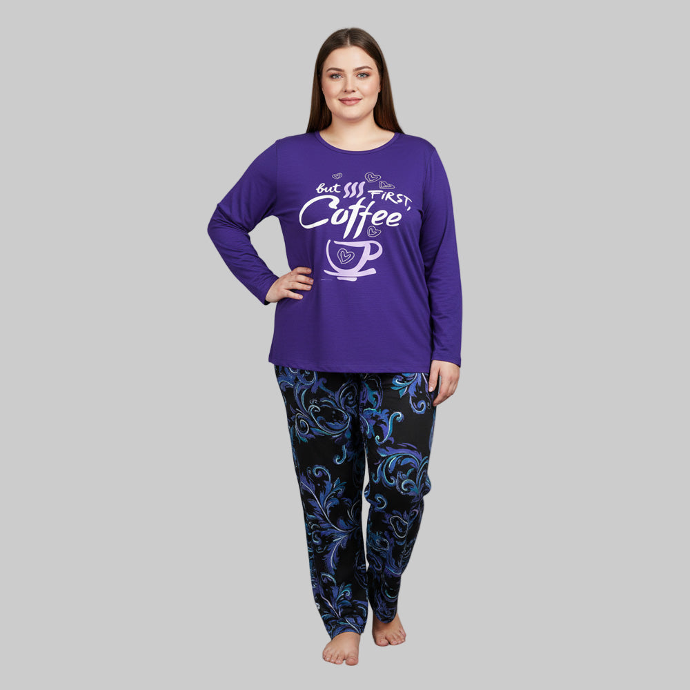 Plus-size woman wearing a purple long-sleeve pajama top with “But First, Coffee” print and printed pajama bottoms — cozy cotton-blend sleepwear set.