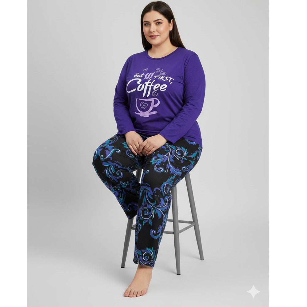 Plus-size woman wearing a purple long-sleeve pajama top with “But First, Coffee” print and printed pajama bottoms — cozy cotton-blend sleepwear set.