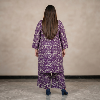 Person wearing a purple patterned outfit standing against a plain background