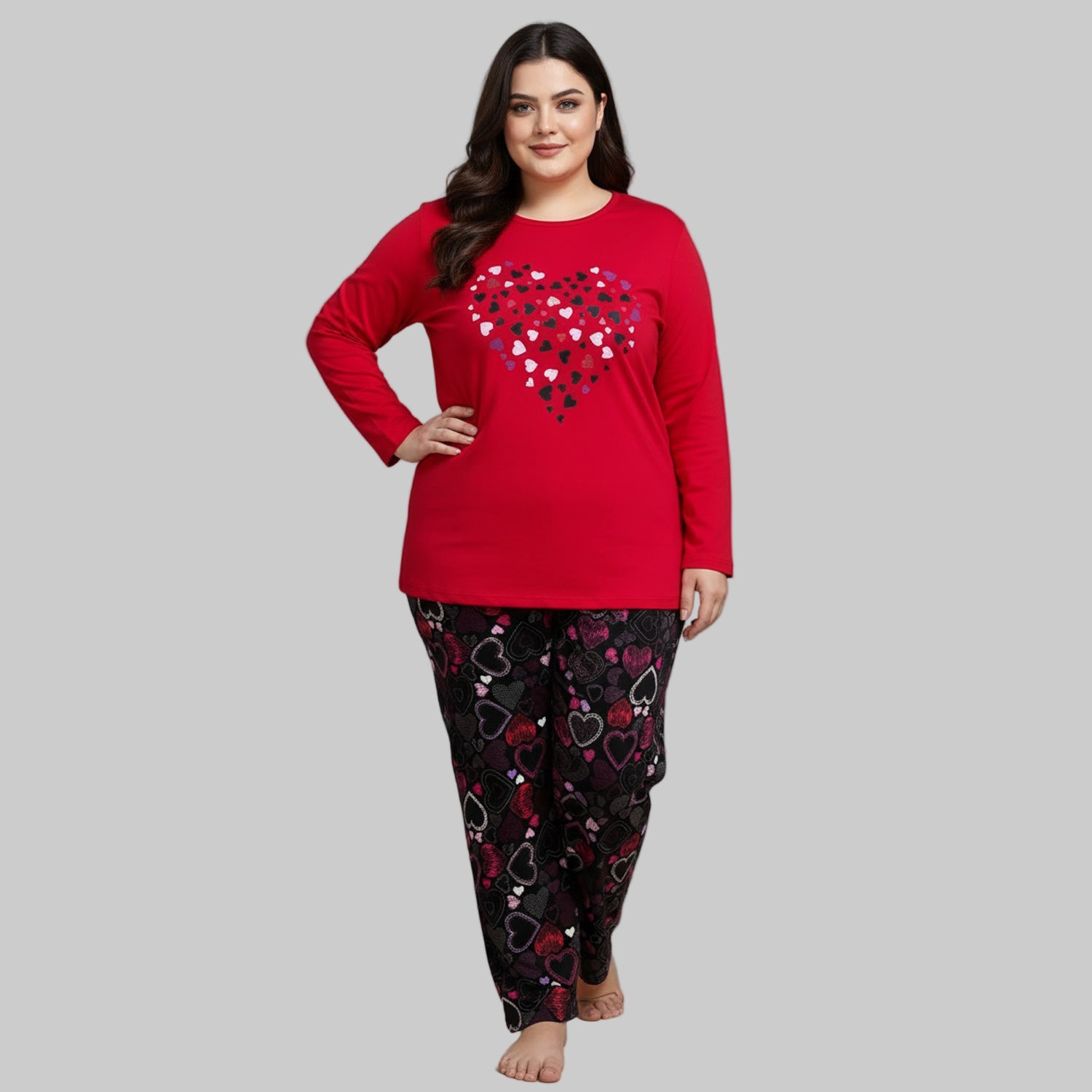 Plus-size woman wearing a red long-sleeve pajama top with heart graphic and black heart-print pajama bottoms — cozy cotton-blend sleepwear set.