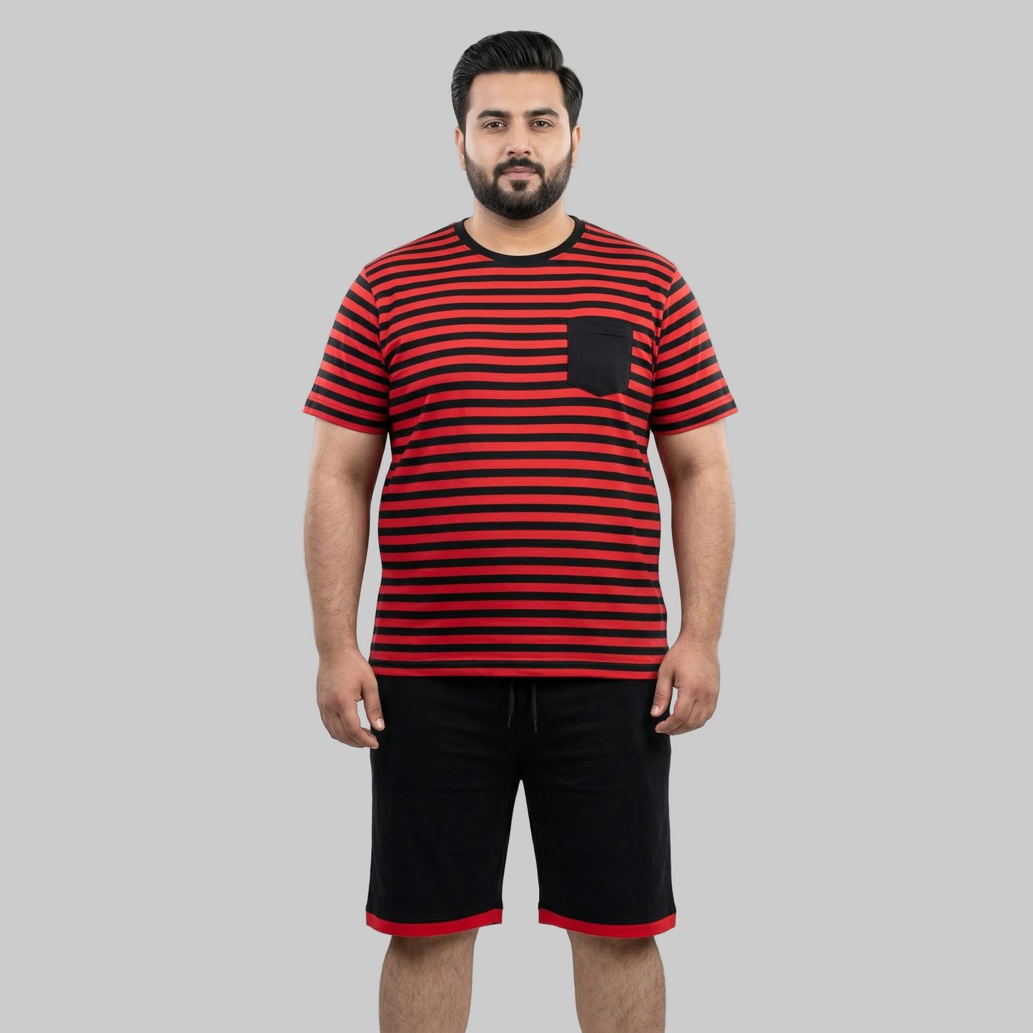 Man wearing a red and black striped t-shirt with a pocket and black shorts on a white background