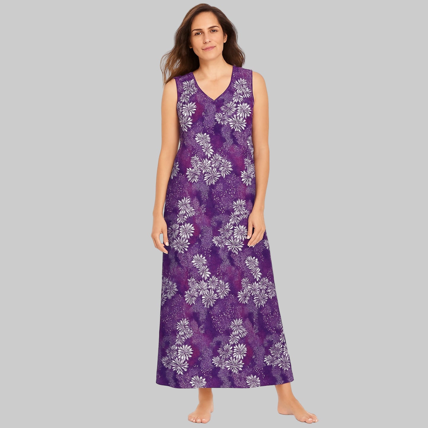 Plus-size woman wearing a rich violet floral sleeveless long lounger, mid-calf length, with V-neck and side pockets on white background.