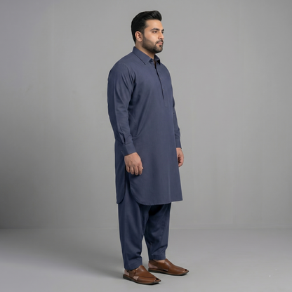 Man wearing a navy kurta with brown shoes on a gray background