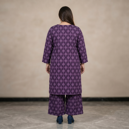 Women wearing a purple patterned outfit standing against a plain background