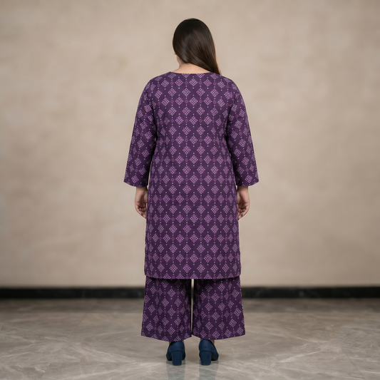 Women wearing a purple patterned outfit standing against a plain background