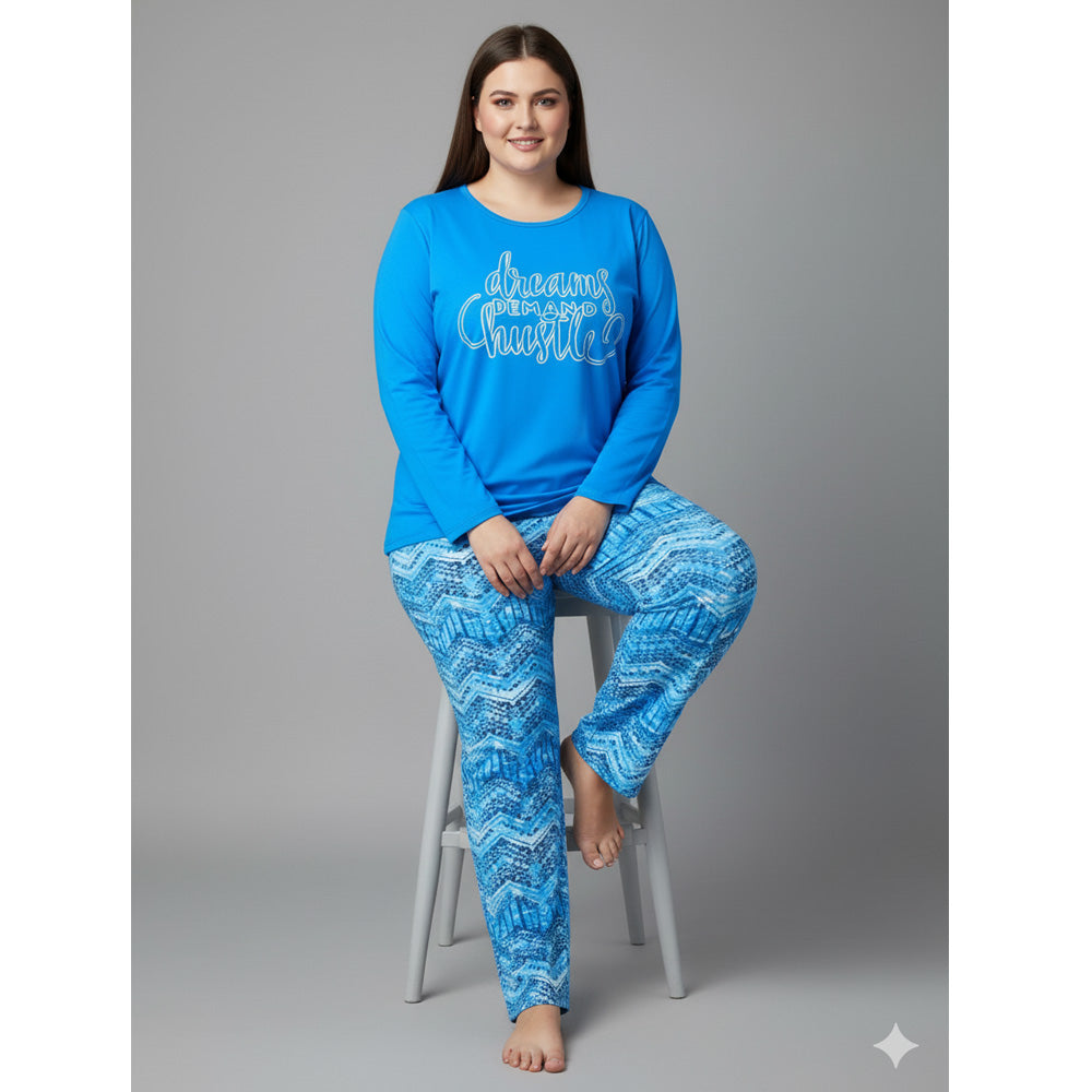 Plus-size woman wearing a sky blue “Dreams Demand Hustle” long-sleeve pajama top with blue abstract print pajama bottoms — soft cotton-blend sleepwear set.