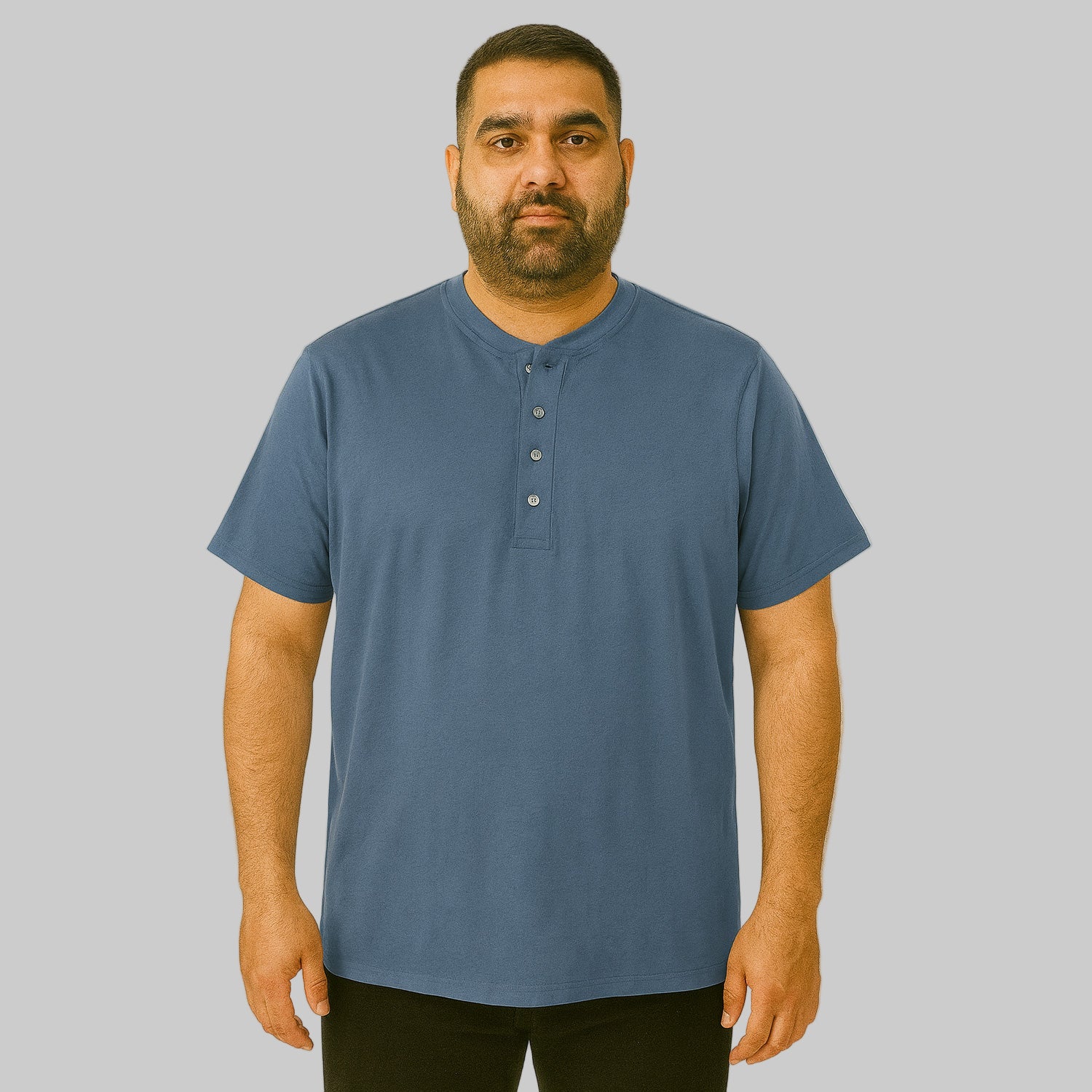 Plus-size Pakistani male model wearing slate blue short-sleeve Henley shirt on a clean studio background, relaxed fit.