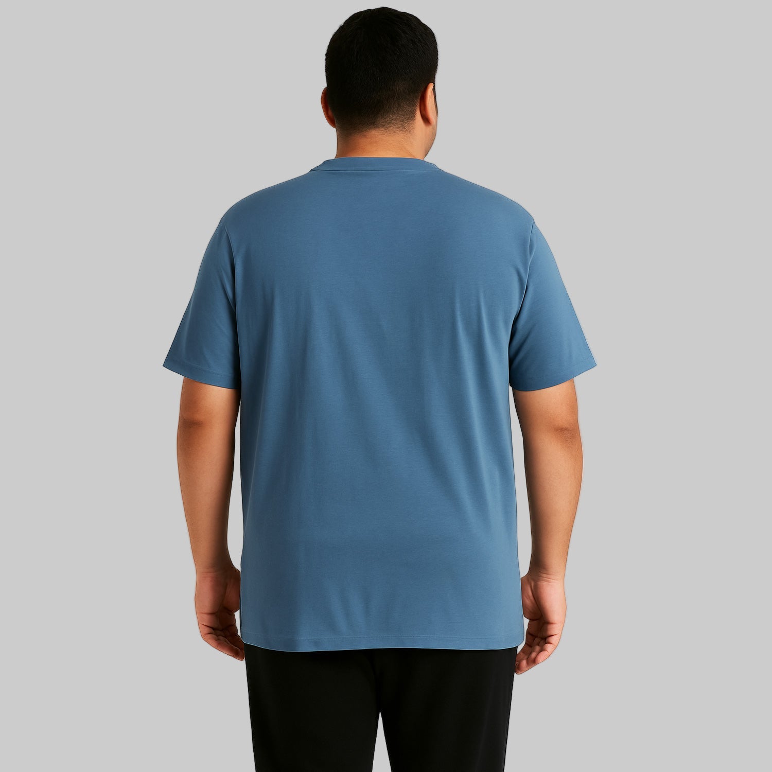 Plus-size Pakistani male model wearing slate blue short-sleeve Henley shirt on a clean studio background, relaxed fit.