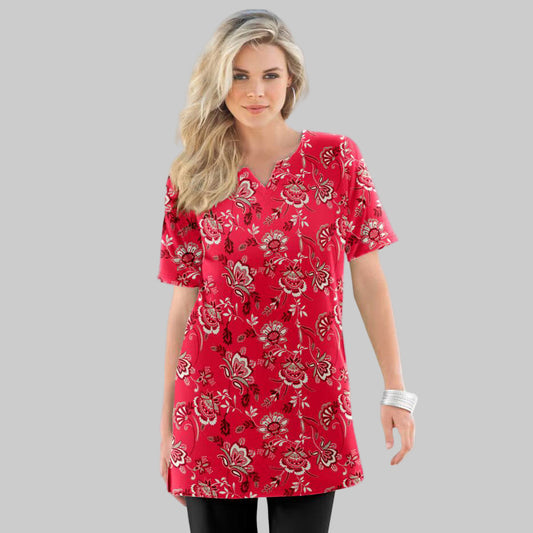 Plus-size woman wearing a vivid red porcelain floral print tunic with notch neckline on a neutral studio background.