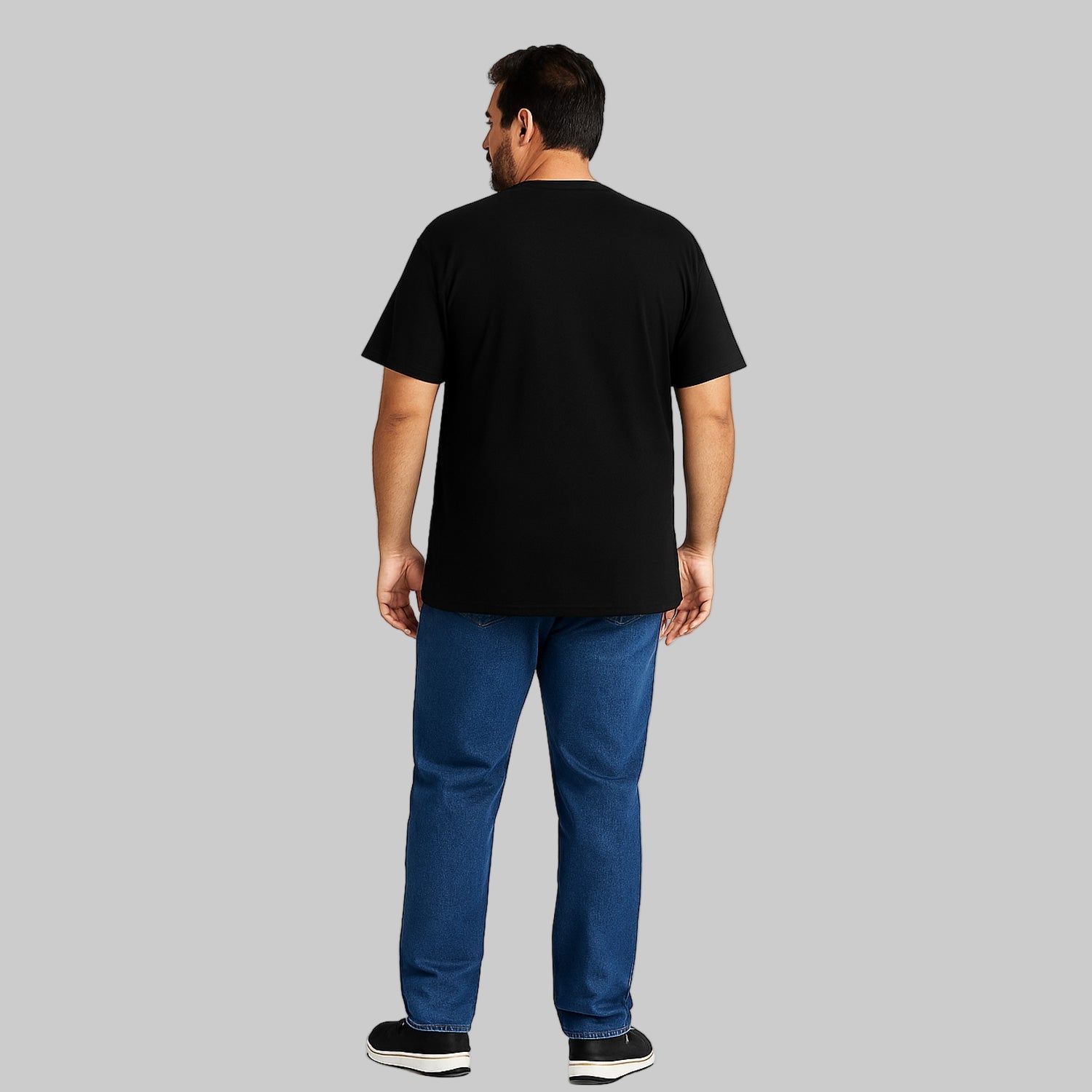 Plus-size Pakistani male model wearing black slogan graphic T-shirt on a studio background, relaxed fit, chest print visible.