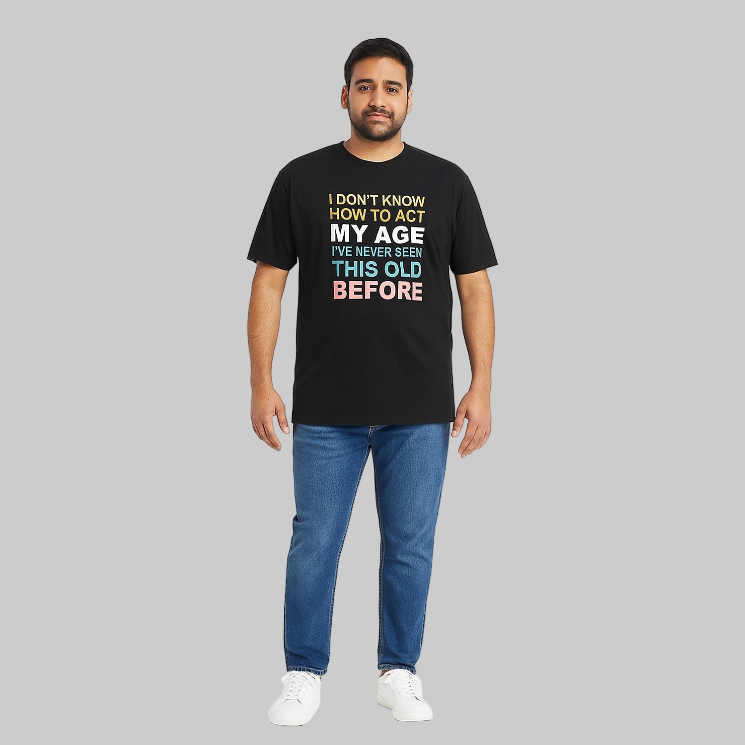 Plus-size Pakistani male model wearing black slogan graphic T-shirt on a studio background, relaxed fit, chest print visible.