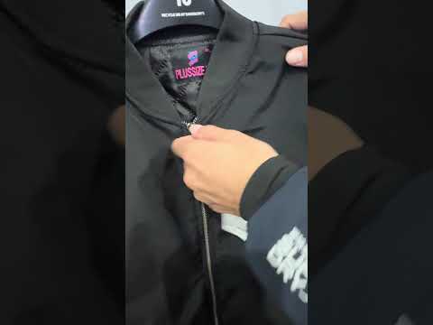 Black plus size bomber jacket with front zip closure and ribbed cuffs displayed on a plain background.